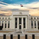 Fed’s Own Watchdog Says The Board Could Have Acted. It DIDN’T. Neoclassical government building with American flag at sunset