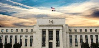 Fed’s Own Watchdog Says The Board Could Have Acted. It DIDN’T. Neoclassical government building with American flag at sunset
