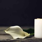 White candle and calla lily on wooden surface