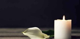 White candle and calla lily on wooden surface