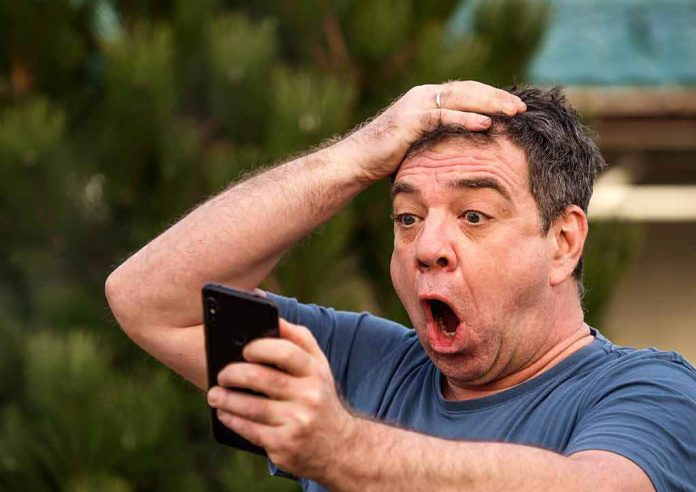 shutterstock_1696247677-1 Exasperated man pressing a hand to his forehead while reading his phone