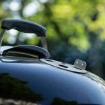 Close-up of a charcoal grill lid with handle and vent