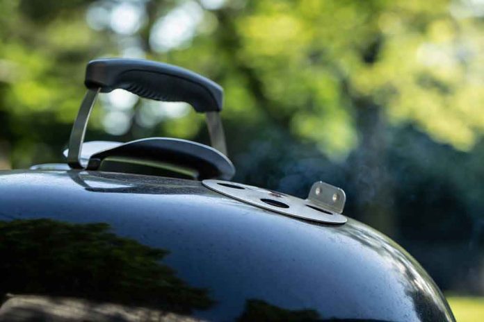 Close-up of a charcoal grill lid with handle and vent