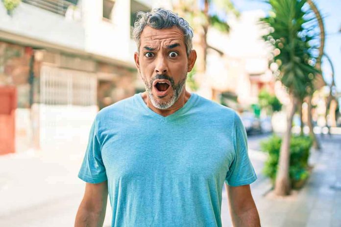 shutterstock_1928530025 Man with surprised expression on a sunny street