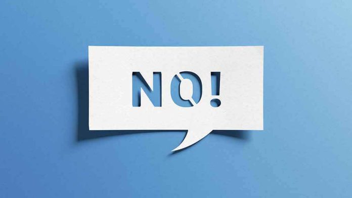 shutterstock_2170050843 Speech bubble with cutout letters spelling NO! on blue background