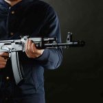 Would-Be Mass Killer’s Weapon Hid A BRILLIANT Secret person holding a rifle against a dark background
