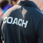 Coach wearing a black shirt with bold lettering