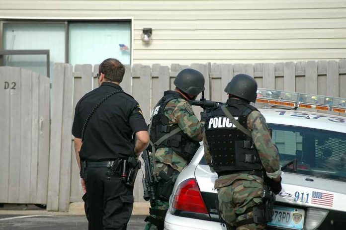 shutterstock_728435-1 police officers in tactical gear beside patrol car